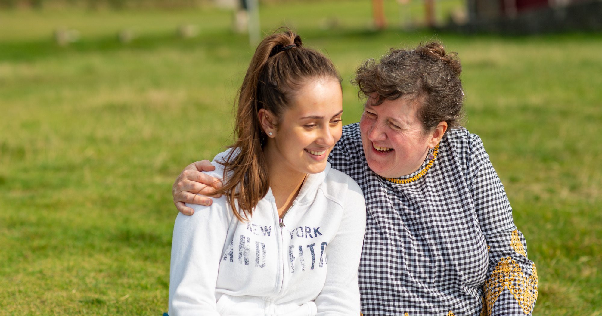 A woman hugging a teenage girl and both laughing